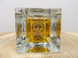 a small square glass candle holder with a label on it