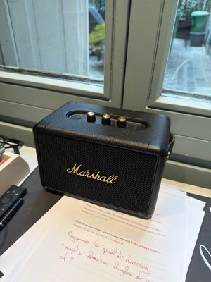 a black speaker sitting on top of a table next to a typewriter