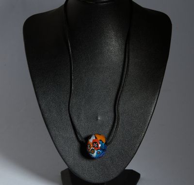 un mannequin noir orné d'une perle de verre bleue et orange