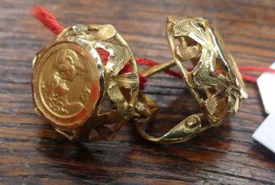 une bague en or ornée d'une pièce de monnaie, posée sur une table en bois