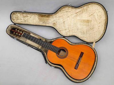 une vieille guitare dans son étui, posée sur une surface blanche