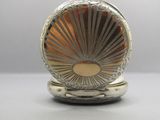 a silver pocket watch sitting on top of a table