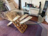 une table en verre avec un piètement en bois au milieu d'un salon