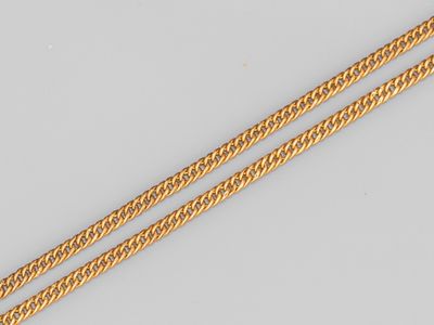 une paire de chaînes en or posées sur une surface blanche