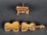 two pieces of jewelry that include a violin, a box, and a piece of wood
