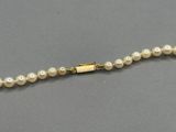 a close up of a pearl necklace with a gold clasp
