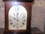 une horloge posée sur une table, avec un mur de pierre en arrière-plan