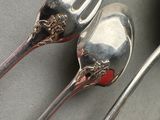 two silver spoons and a fork on a table