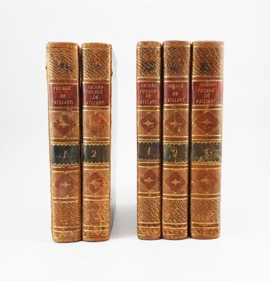 trois vieux livres posés l'un sur l'autre sur une surface blanche