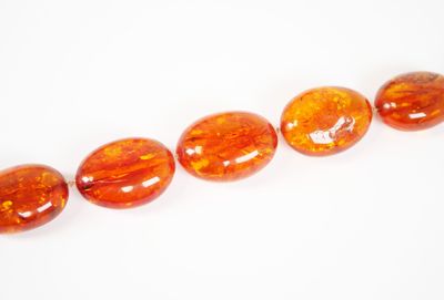 une rangée de perles de verre orange sur un fond blanc