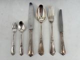 a silverware set on a table with a knife, fork, spoon, and spoon rest