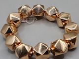 a close up of a bracelet made of gold metal beads