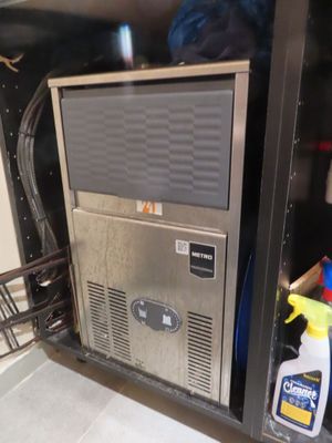 un micro-ondes placé à l'intérieur d'un placard, sur lequel est posé un vaporisateur