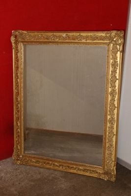 a mirror sitting on the floor next to a red wall