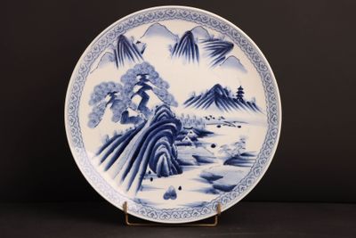 a blue and white plate with a mountain scene on it