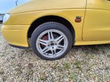 a yellow car that is parked in a gravel lot