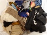 a pile of clothes in a white bag on a bed
