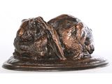 statue représentant deux chiens couchés sur une assiette, sur fond blanc