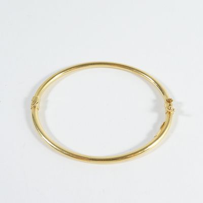 gros plan d'un bracelet en or sur une surface blanche