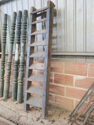 une échelle appuyée contre un mur de briques, à côté d'un tas de vieux outils