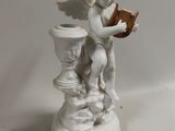 a small statue of a cupid reading a book