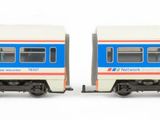 two trains that are sitting side by side on a white surface