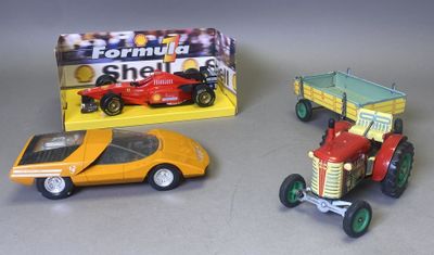 trois petites voitures et un petit tracteur posés sur une table