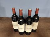three bottles of red wine are lined up on a wooden table