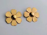 une paire de boucles d'oreilles à clous en forme de fleur, de couleur dorée, sur fond blanc