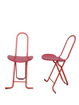 pair of red metal folding chairs on a white background