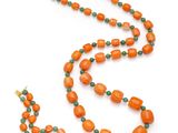 un collier composé de perles orange et vertes, muni d'un fermoir doré