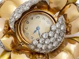 a gold and diamond flower brooch with a clock on it
