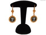 une image représentant une paire de boucles d'oreilles sur laquelle figure le portrait d'une femme