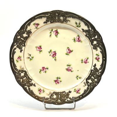 une assiette blanche ornée de fleurs roses, posée sur un socle