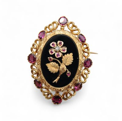 une broche noire et dorée ornée d'une fleur entourée de saphirs roses