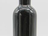 a black bottle with a green lid sitting on a white surface