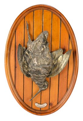 a metal bird on a wooden plaque mounted on a wall