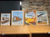 three framed posters on a table in front of a stone wall
