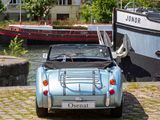 a small blue car parked next to a boat on the water