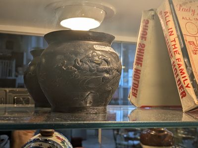 de nombreux vases et livres posés sur une étagère dans une pièce