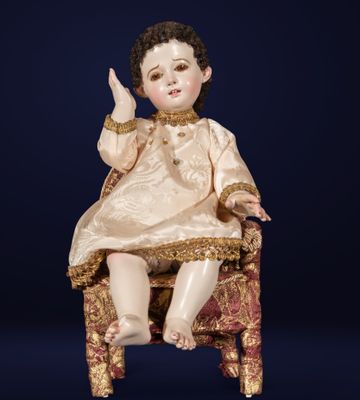 an antique doll sitting on a chair with a gold dress