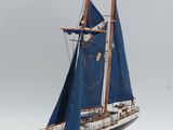 a model of a sailboat with blue sails on a wooden stand