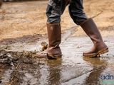 a person standing in a puddle of mud with a pair of boots