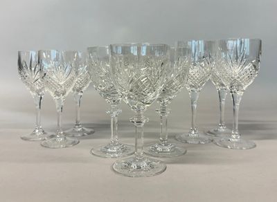 six crystal wine glasses are lined up on a white surface