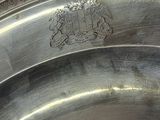 a close up of a silver plate with a coat of arms on it