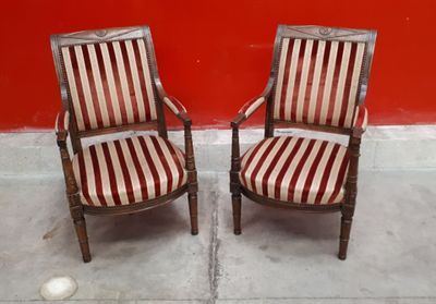 une paire de chaises anciennes aux assises rembourrées à rayures, devant un mur rouge