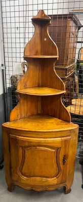 une armoire d'angle en bois surmontée d'une étagère