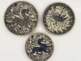 trois assiettes ornées de motifs sont posées sur une surface blanche