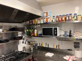 stainless steel counter top in a commercial kitchen with a microwave above it