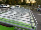 a green bus with a metal roof rack on it